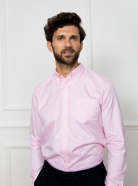 Man wearing a pale pink long sleeved shirt with a button down collar made with 100% Royal Oxford Cotton.